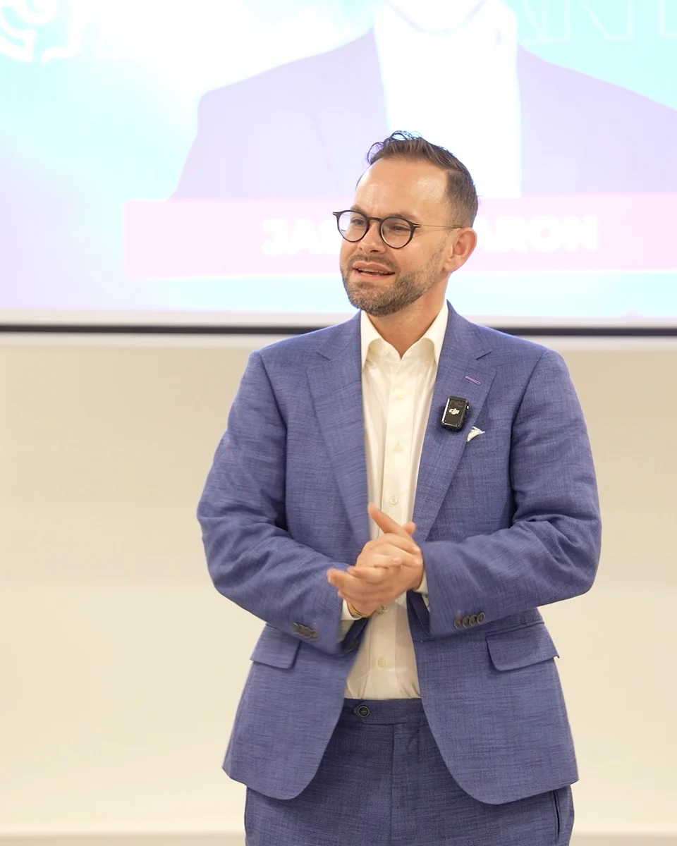 Jason Baron speaking, wearing a blue suit and a lapel microphone